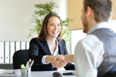 Two professionals shaking hands in a bright office setting.