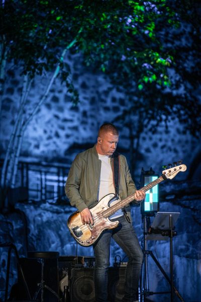 Man playing electric bass guitar on stage at night.