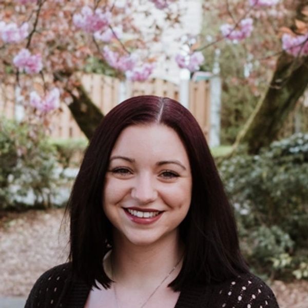 Mindfulness Teacher, Natalie, smiling in park with pink cherry blossom tree