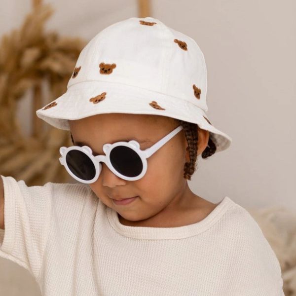 Child wearing a white hat with bear designs and white sunglasses.