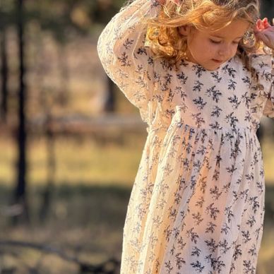 Young girl with curly hair in a floral dress outdoors.