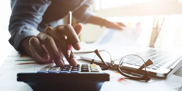 Close up of businessman or accountant hand holding pen working on calculator to calculate business d