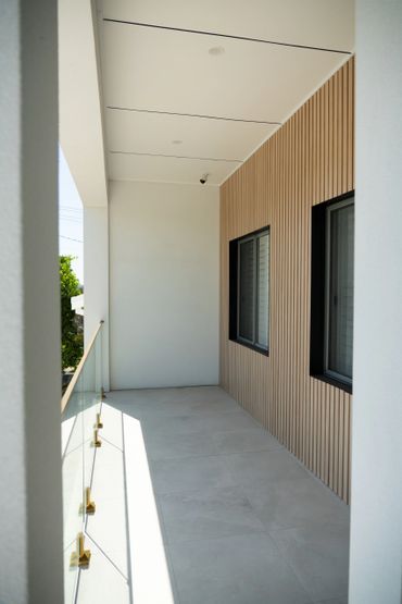 Modern balcony with wood paneling and glass railing.