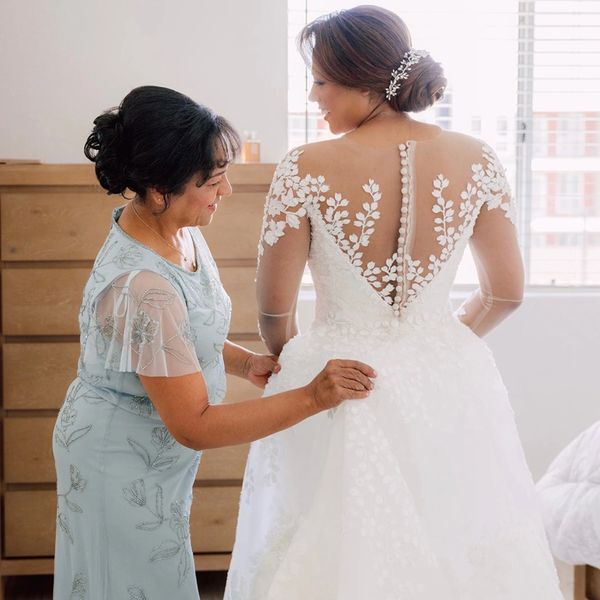 Teresa, owner of Bridal City, carefully helps a bride into her wedding gown during a personalized br