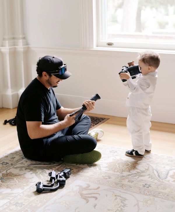 Man and toddler with cameras indoors.