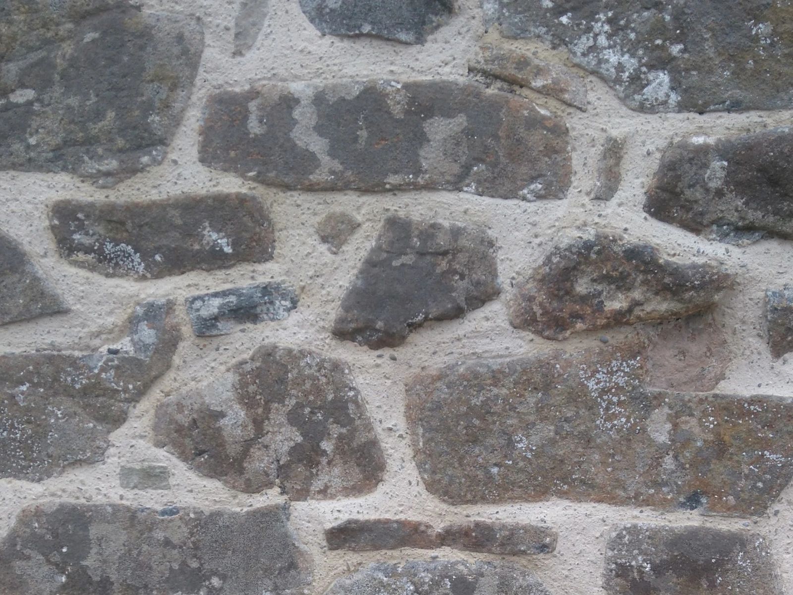 Close-up of a stone wall with irregularly shaped rocks and mortar.