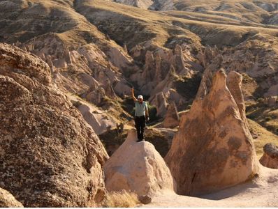 Man standing atop a rock formation in a rugged, rocky landscape.