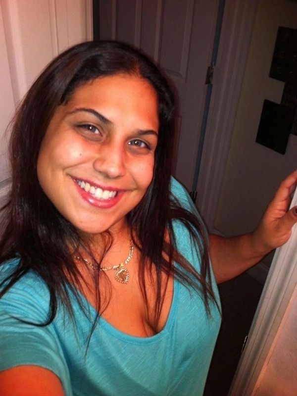 Smiling woman wearing a turquoise top and heart-shaped necklace.