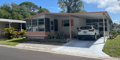 A single-story house with a car parked in the driveway under a carport.