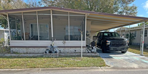 A mobile home with a carport and a black truck parked outside.