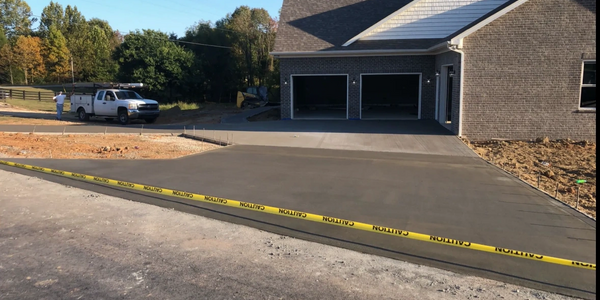 Newly poured concrete driveway in front of a residential house.