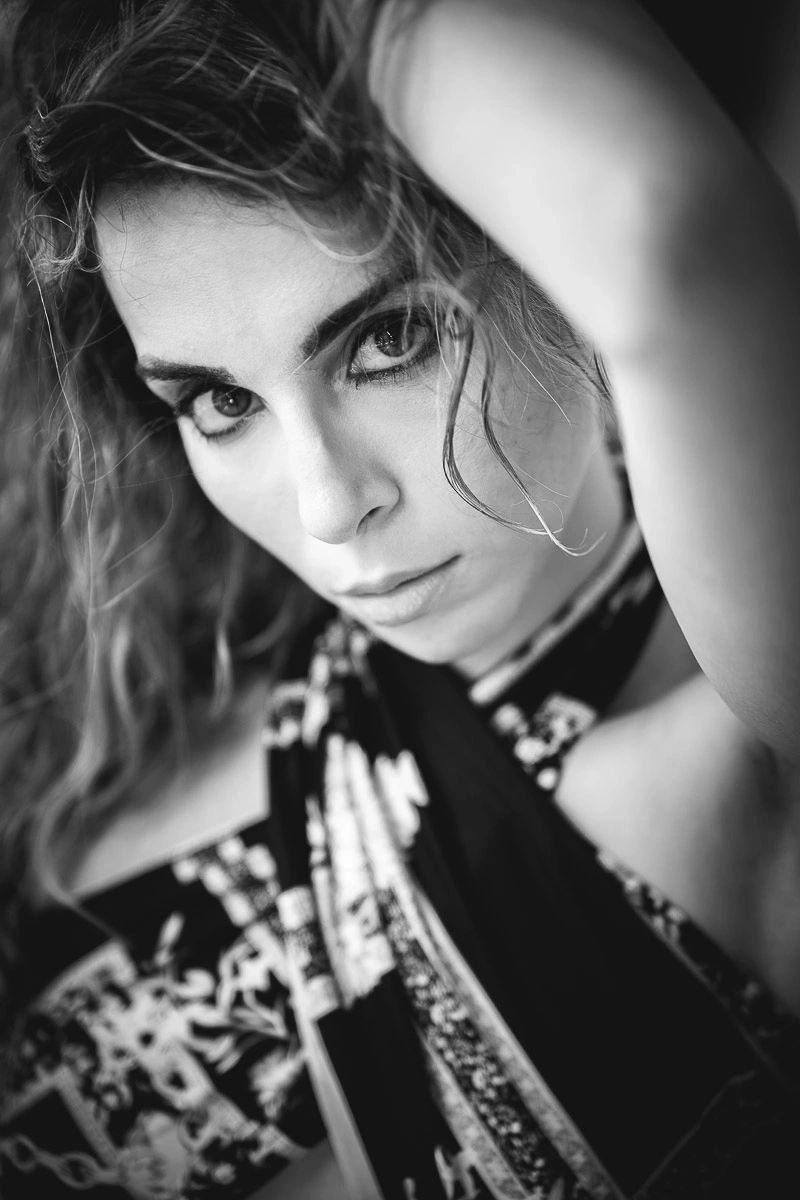 Black and white close-up portrait of a woman with intense eyes and flowing hair.
