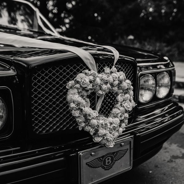 Vintage black wedding car decorated with a romantic floral heart arrangement for a Southern California wedding