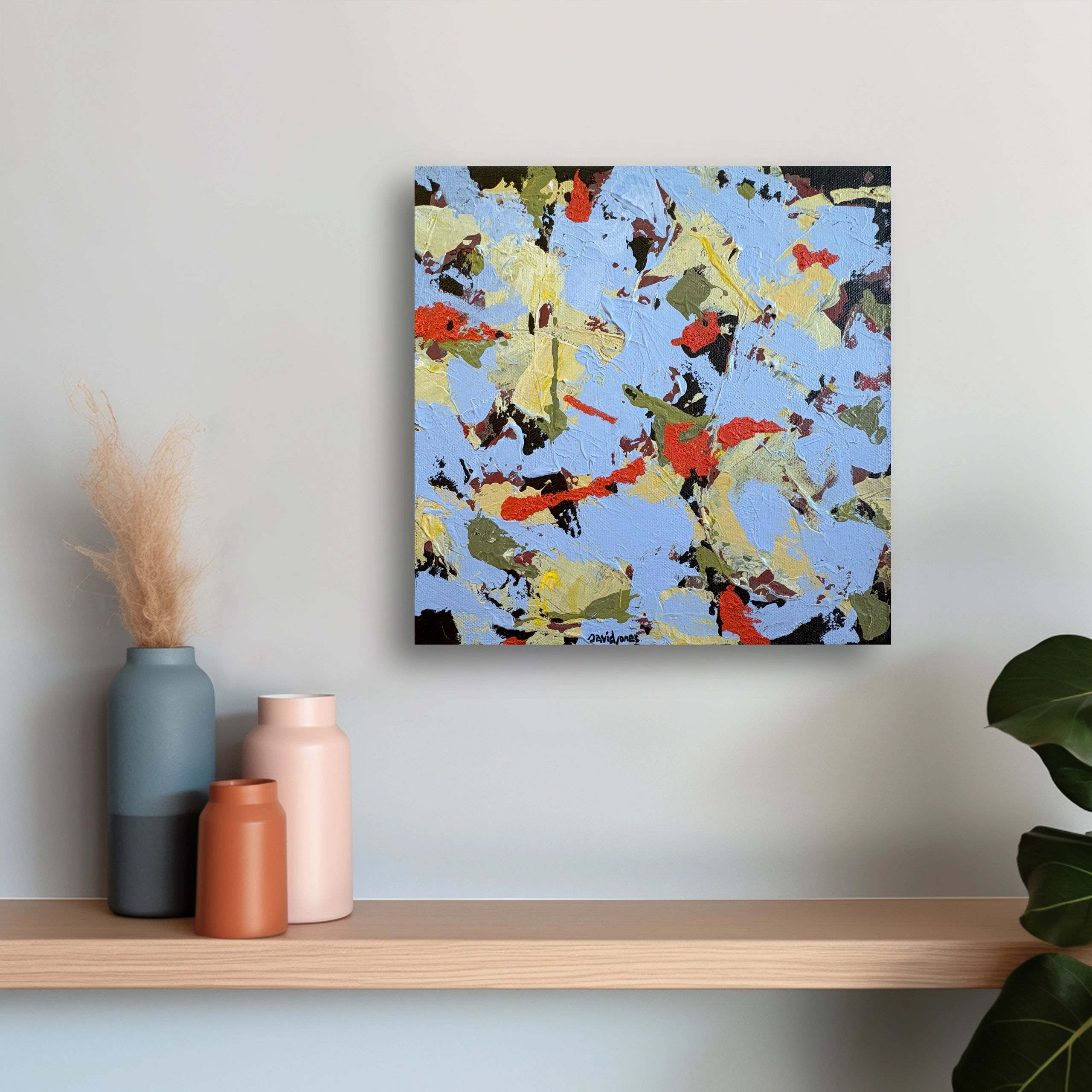 Colorful abstract painting on a wall above vases.