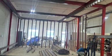 Construction workers building a metal frame structure indoors.