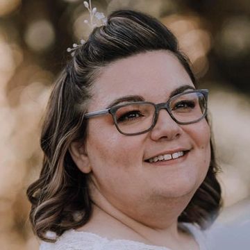 Smiling woman wearing glasses with hair accessory.