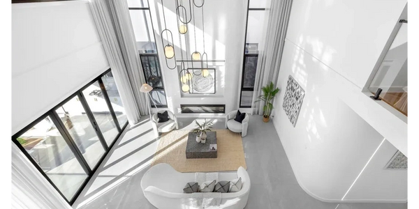Bright modern living room with white furniture and tall windows.