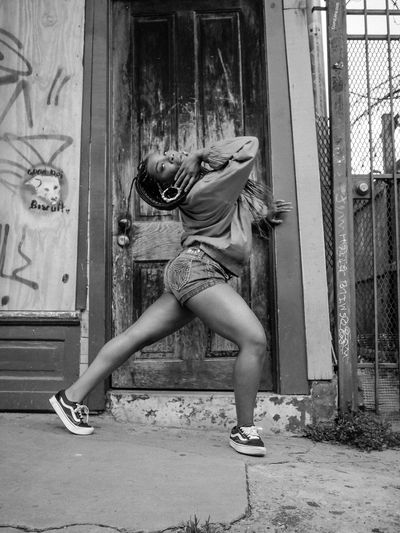 Woman striking a dynamic dance pose in urban setting.