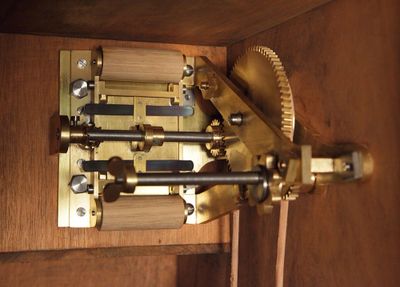 Close-up of a vintage mechanical device with brass gears and wooden rollers.