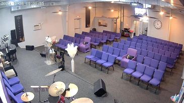Empty church sanctuary with purple chairs and musical instruments on stage.