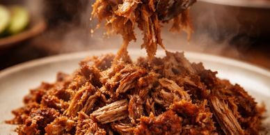 Close-up of steaming pulled pork on a plate.