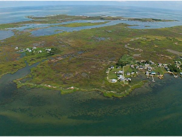 Aerial view of a coastal island with marshlands and scattered houses.