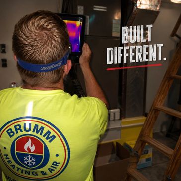 Technician uses thermal camera, wearing Brumm Heating &amp; Air shirt, with text 'Built Different.'