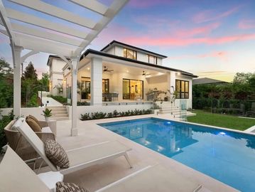 Modern house with a pool and lounge chairs at sunset.