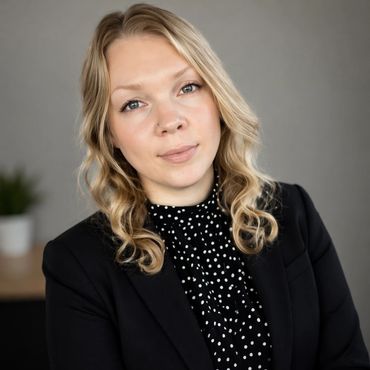 Professional woman in black blazer and polka dot blouse.