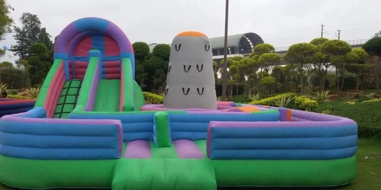 Colorful inflatable playground with slide and climbing wall outdoors.