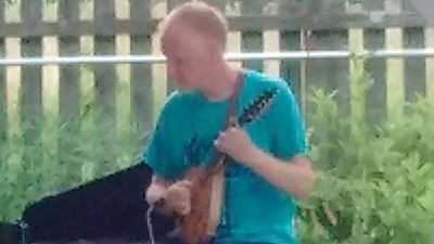 A man playing a string instrument outdoors.