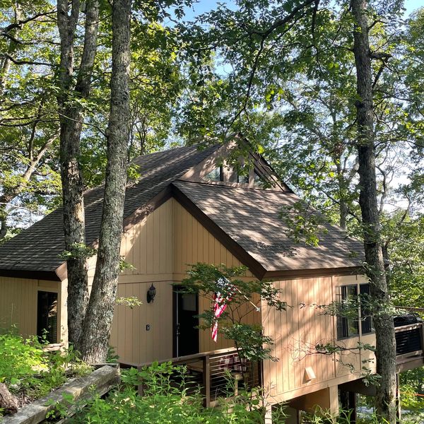 A cozy cabin in the woods with an American flag.