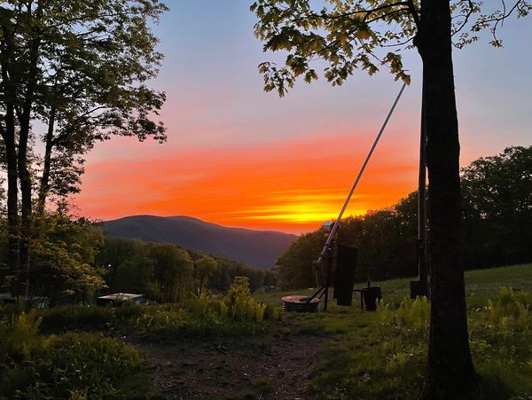 Sunset over a mountain landscape with trees in the foreground.