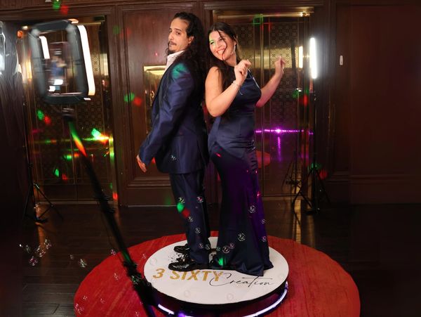 Couple posing back to back in formal attire with colorful lights.