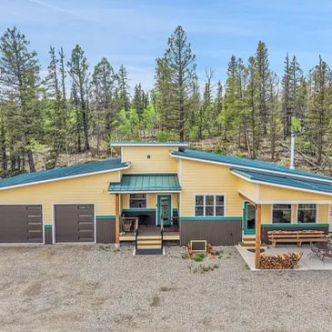 Yellow and brown cabin with a green roof in a forested area.