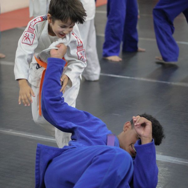 Two kids practicing judo in a dojo.