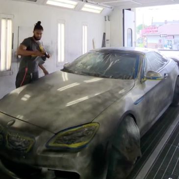 Man preparing a car for painting inside a spray booth.