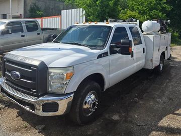 White Ford utility truck with extended cab parked outdoors.