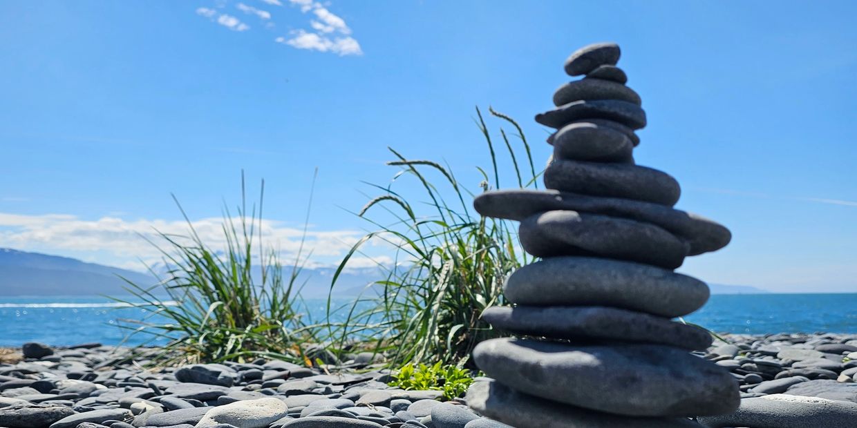 Tower of flat rocks and clear blue sky on the beach in Homer, Alaska.