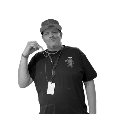 Man wearing a cap and black shirt, holding a necklace and making a confident face.