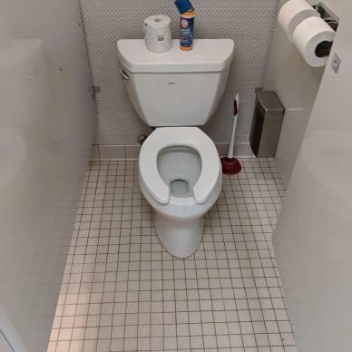 Clean white toilet in a small tiled bathroom stall.