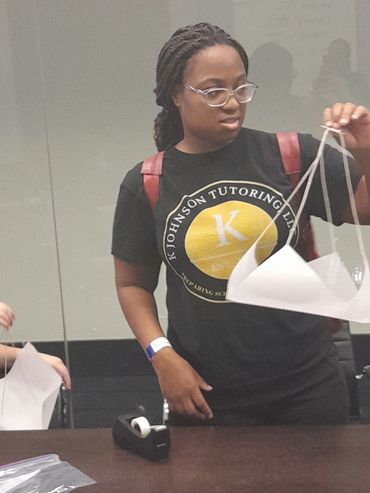  Student holding white paper structure.
