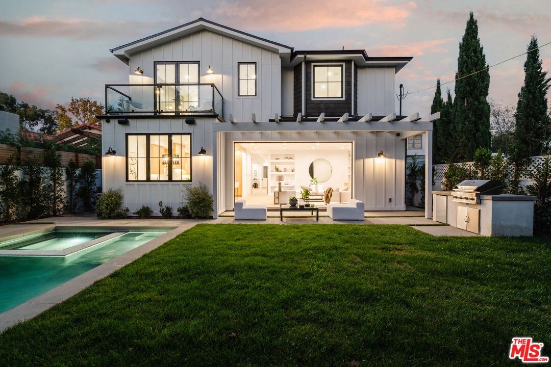 Modern two-story house with a pool, patio, and outdoor grill at dusk.