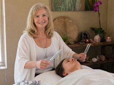 A woman performing a sound healing therapy on a client lying down.
