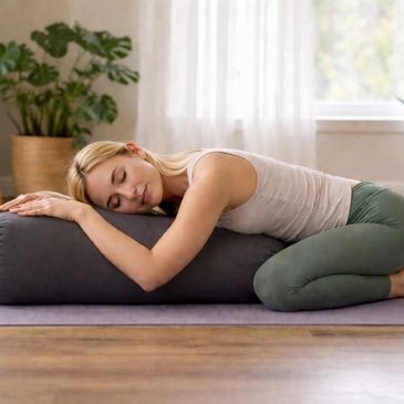 Woman resting on a bolster pillow in a serene room.