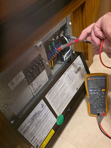 Measuring voltage inside a furnace panel with a multimeter.