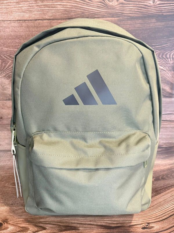 Green Adidas backpack on wooden surface.