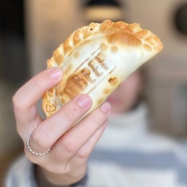 Hand holding a baked pastry with text.