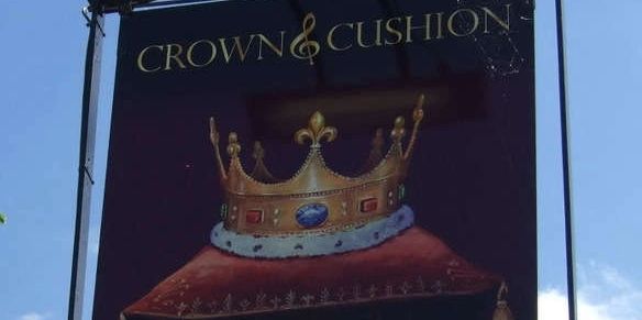 Signboard with a crown on a cushion under the text "CROWN &amp; CUSHION".