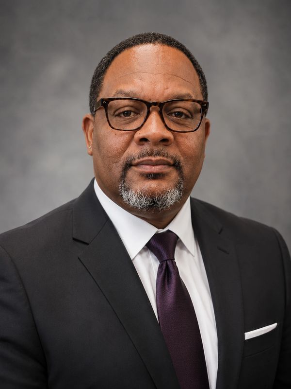 Professional man in suit and glasses posing for a formal portrait.